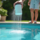 Personne verse du bicarbonate dans une piscine d'été brillante